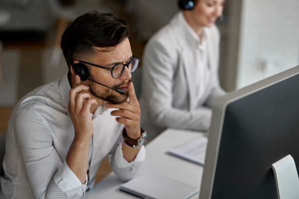 Concentrated call center agent talking with a customer while working in the office.